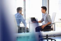 2 men sitting at a desk.