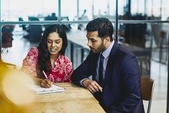 Woman and man working together sitting at a table and taking notes. 